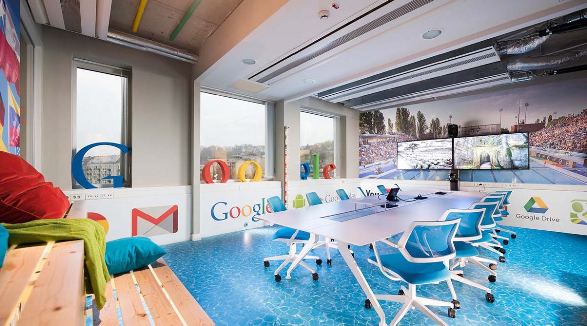 A Google Budapest iroda tárgyalóterme nyomtatott, vizet imitáló padlóval, hatalmas plasztikus Google felirattal az ablakokban, nagyméretű képernyőkkel és egyéb díszletekkel berendezve.